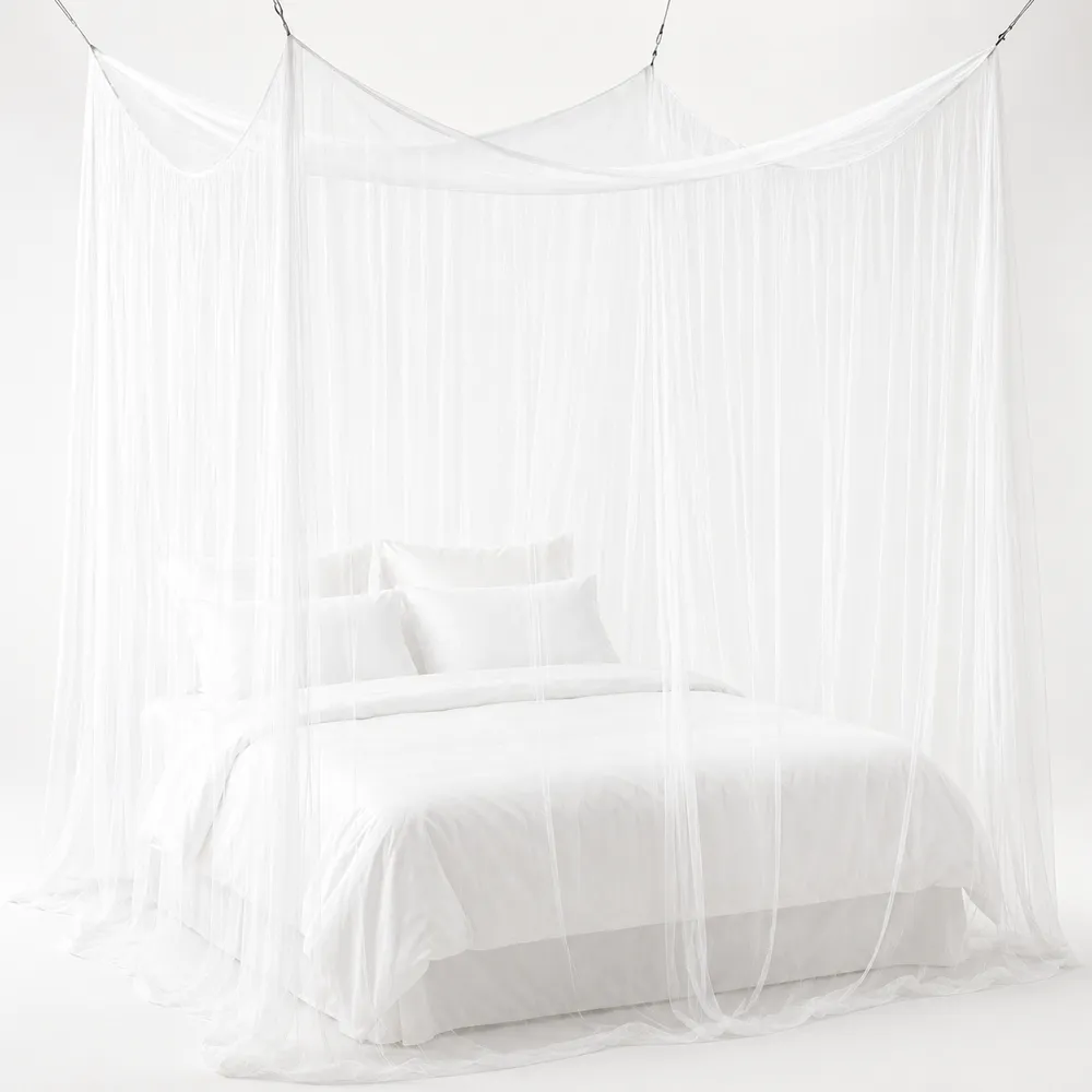 White canopy mosquito net softly framing a made bed in a light bedroom